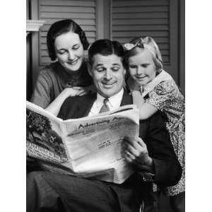 Man Reads the Advertising Age, While Wife and Daughter Read Over His 