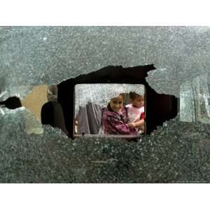  An Iraqi Woman with a Child Peers Through a Shattered Window 